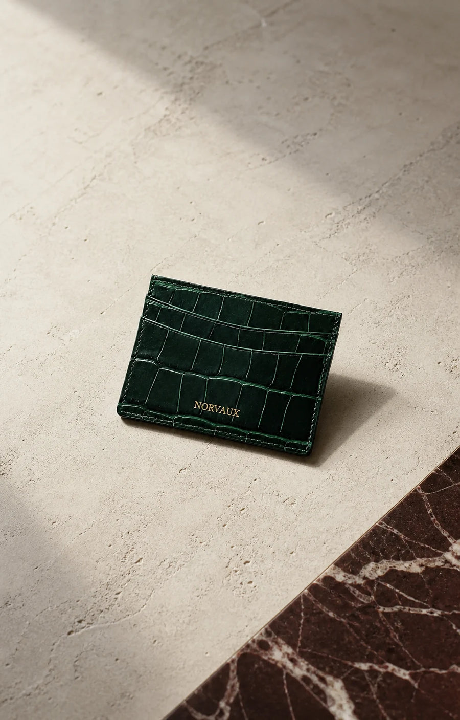 CROVÉ Emerald green calf leather cardholder arranged on dark marble and pale stone