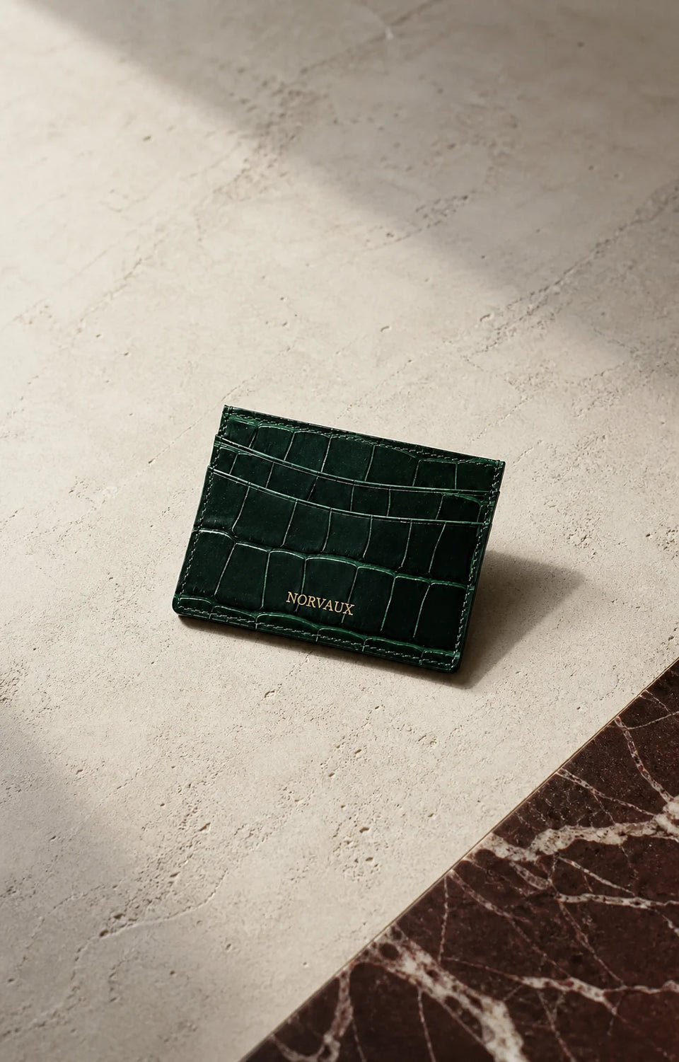 CROVÉ Emerald green calf leather cardholder arranged on dark marble and pale stone