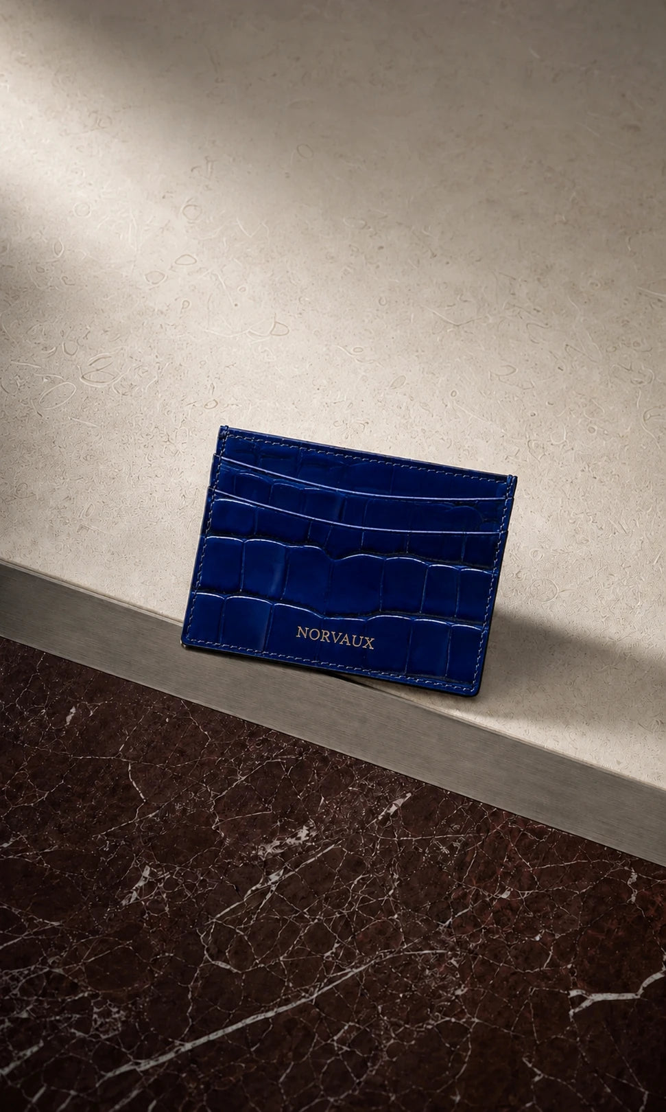 CROVÉ Ocean blue calf leather cardholder arranged on burgundy marble and brushed metal