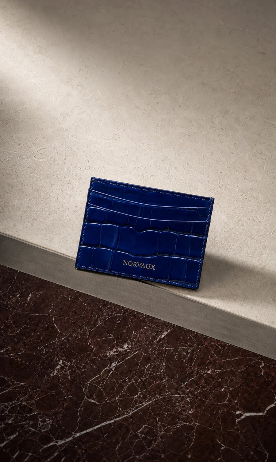 CROVÉ Ocean blue calf leather cardholder arranged on burgundy marble and brushed metal